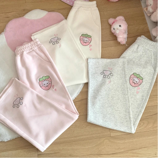 Pink, white, and grey kawaii pants with strawberry puppy design on a wooden floor.