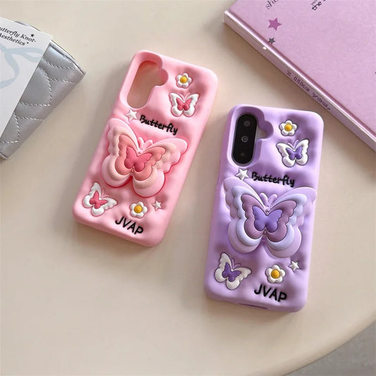 This image is showing two designs that are available for the Kawaii Butterfly Samsung Phone Case, one option is the pink design with a large 3D butterfly in the middle which is a phone grip with smaller butterflies around it and some white flowers, the other option is of this the same design but in purple.