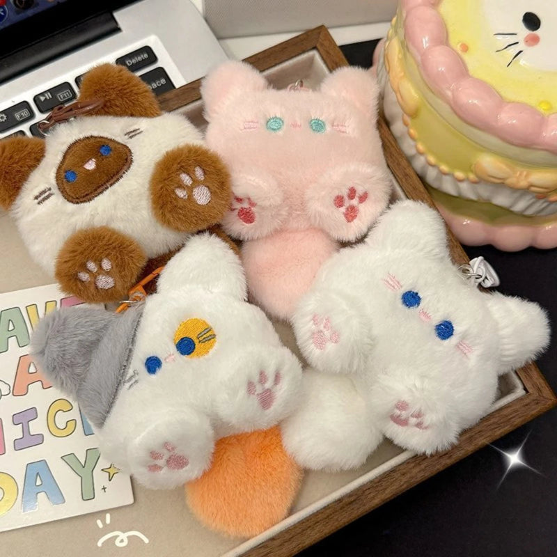 Set of cute plush keychains on a desk with a laptop and stationery items.