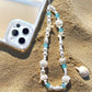 Mermaid treasure phone charm bracelet displayed on sandy beach