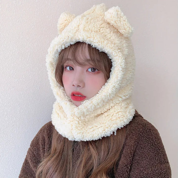 Person wearing a cream-colored hat with kawaii bear ears on a plain background
