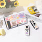 Gaming console with cartoon cat designs on a white surface with a floral arrangement in the background.