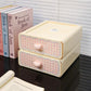 Small beige storage box with pink checkered pattern and heart knobs on a reflective surface.