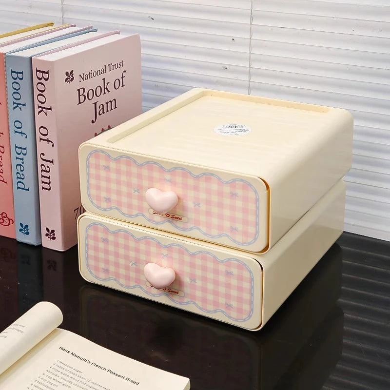 Small beige storage box with pink checkered pattern and heart knobs on a reflective surface.