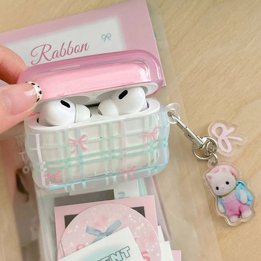 Pink and clear airpod case with bow design and matching keychain on a wooden surface