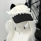Mannequin head with a black cap featuring white decorative elements, white wig, and silver necklace.
