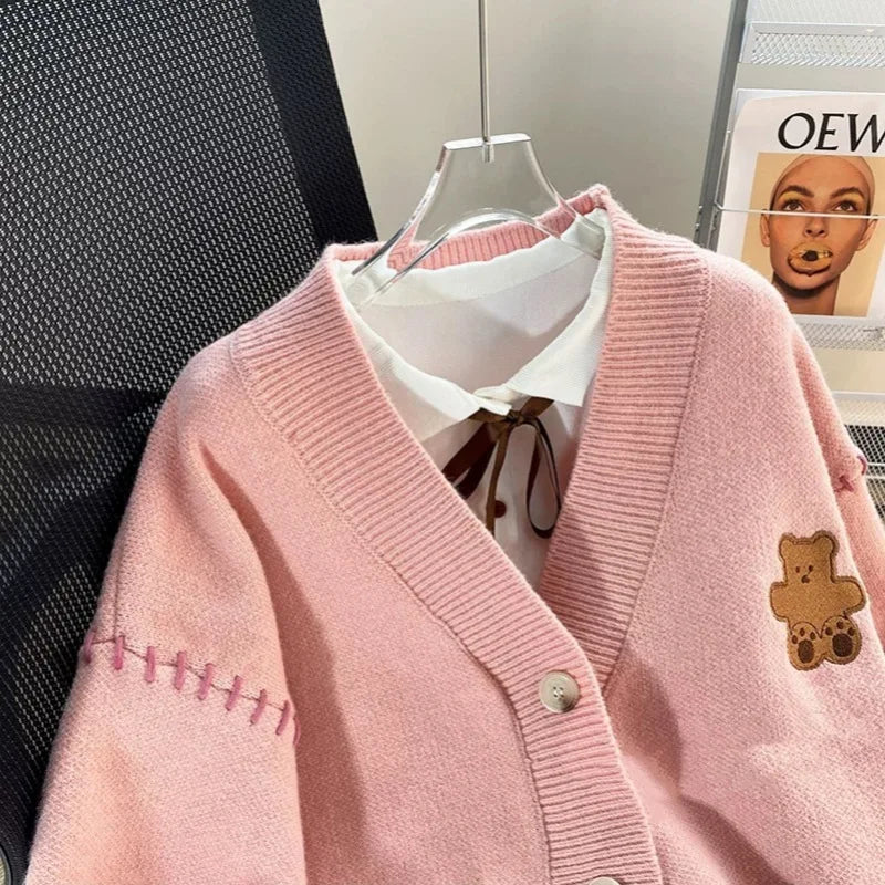 Sweet Teddy Bear Cardigan pastel pink edition with a bear sown into the chest area whilst the sleeves have large black stitches where they have been joined and black strips on the wrist cuffs and black and pink trim. 