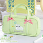 Light green pencil case with cartoon cat design and pink bows on a white surface.
