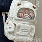 beary cute backpack with bear ears and a visible brand logo on a textured surface , white version