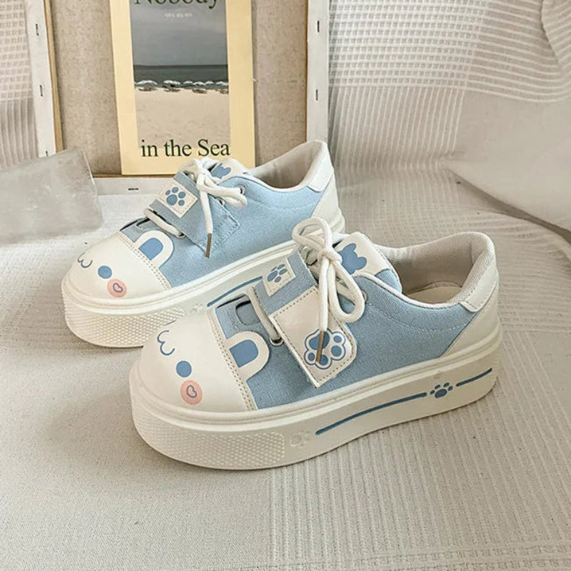 Pair of blue and white cute cat sneakers with decorative elements on a light background
