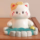 Cute resin figurine of a cat in a onsen with a yellow towel on its head on a wooden surface.