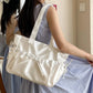 Woman holding a white handbag in a room with curtains and a light switch.