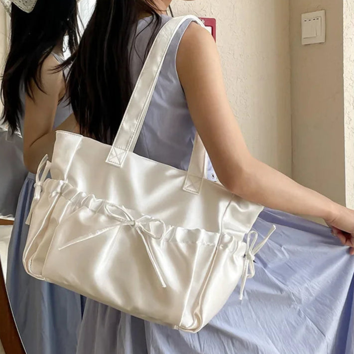 Woman holding a white handbag in a room with curtains and a light switch.