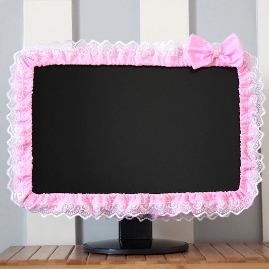 Computer monitor with a pink lace cover on a wooden surface.