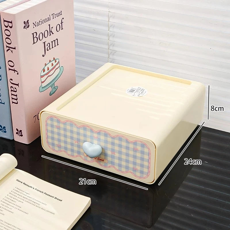 Small rectangular box with checkered pattern and heart-shaped handle on a surface with books in the background.