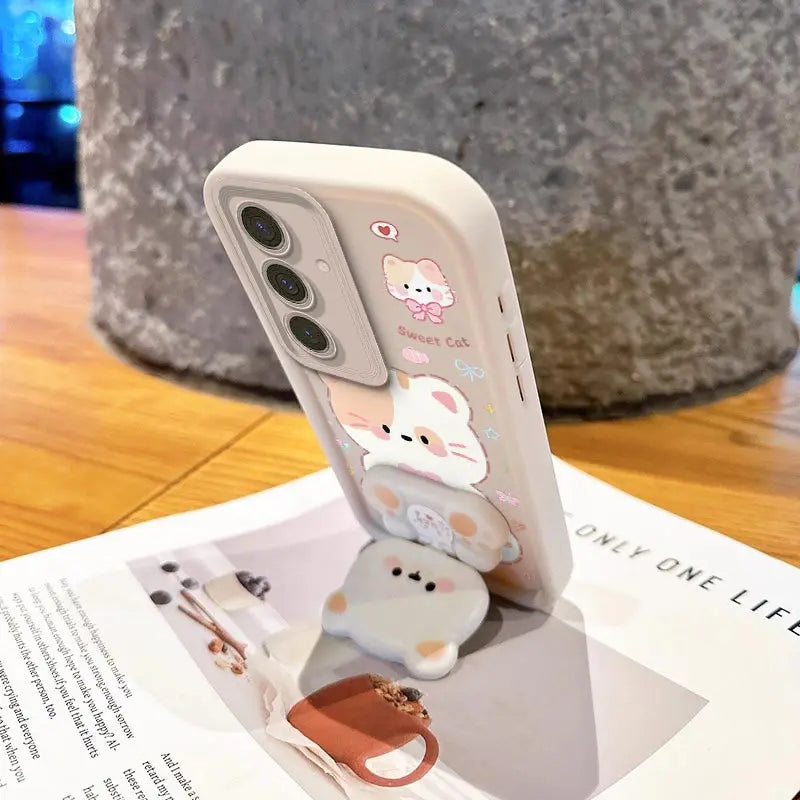 This women has position the phone into a stand position using the phone stand attached to the Kawaii Cuties Samsung Phone Case, showing a closer view of the design of the case which features a sweet cat and a bear as a phone stand, which also includes the mirror when you position its head a certain way.