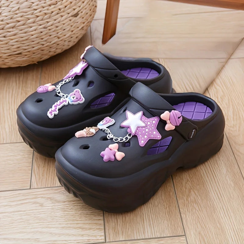 Black sandals with purple and pink stars and bows decorations on a wooden floor