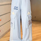 Light blue pants with kawaii cat designs on a wooden floor.