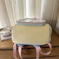 Pastel Yellow bottom view of the kawaii backpack on a wooden surface.