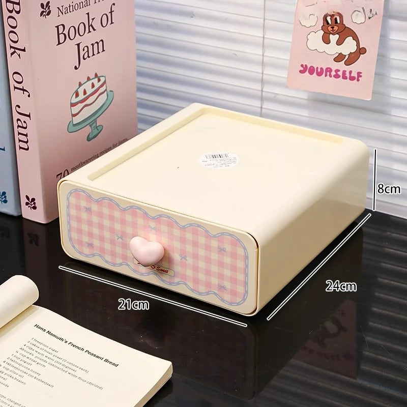 Small rectangular kawaii storage box with a pink checkered pattern on a reflective surface with books in the background.