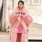 Person wearing a pink fur coat holding sunglasses indoors.