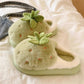 Pair of green plush slippers with leaf design on a soft surface