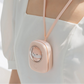 Pink electronic device with a small shiba inu screen and strap worn by a person in a white outfit.