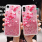 Two pink sakura phone cases with glitter held by a person.