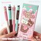 Four colorful gel pens with cartoon animal toppers and their packaging held by a hand.