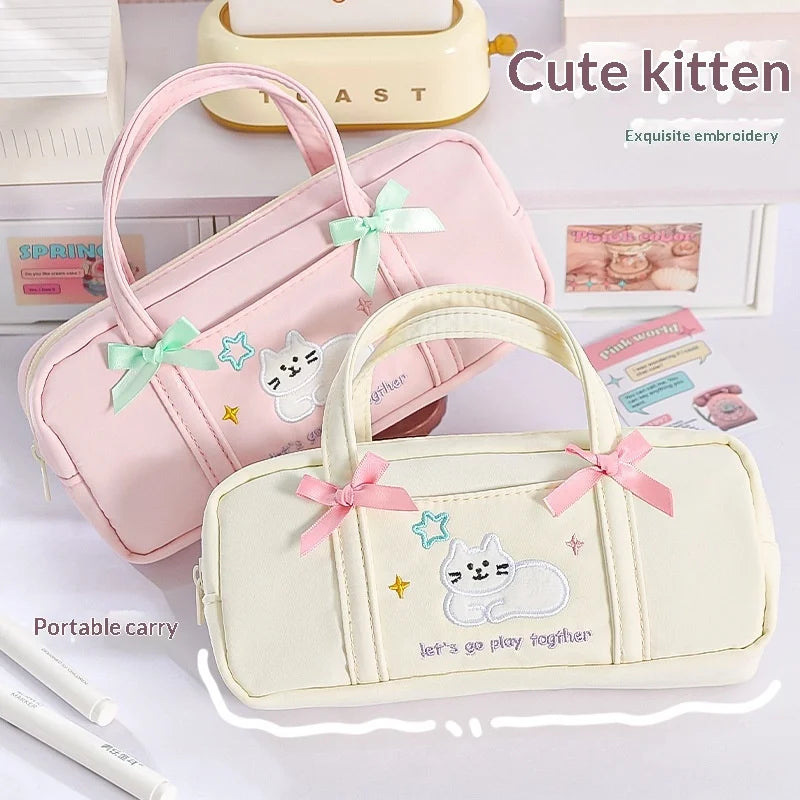 Two pencil cases with cute kitten designs and embroidered text on a light background.