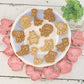 Set of animal-shaped cookie cutters on a white plate with cookies shaped like animals.