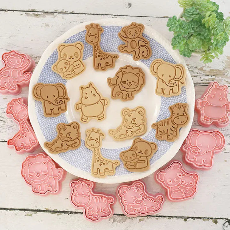 Set of animal-shaped cookie cutters on a white plate with cookies shaped like animals.