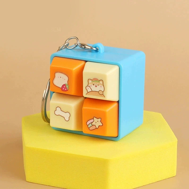 Colorful cube-shaped keychain with cartoon designs on a beige background