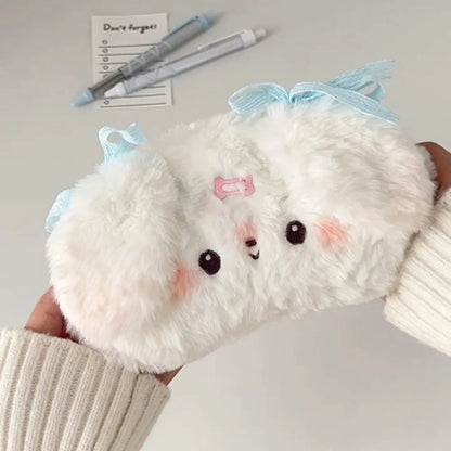 Plush white puppy pencil case  with a blue bow held by a person.