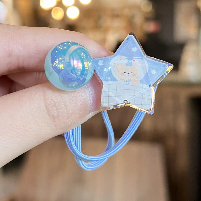 Star-shaped hair tie with a cartoon design held by a hand against a blurred background