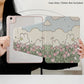 a women holding the Kawaii Tulips & Bunnies iPad Case being displayed on an ipad, bunnies in a tulip meadow with fluffy white clouds and blue sky is on the case itself.