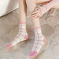 Person wearing pink and white checkered socks on a stone floor