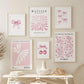 A set of six framed art prints with a cohesive pink and white aesthetic, displayed on a beige wall above a white console table with decorative items.