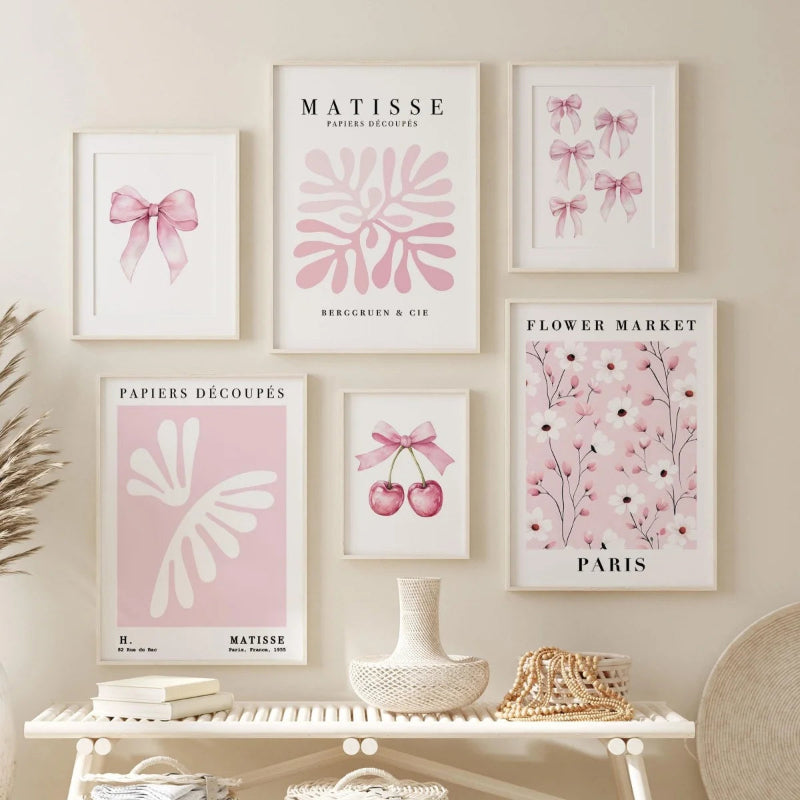 A set of six framed art prints with a cohesive pink and white aesthetic, displayed on a beige wall above a white console table with decorative items.