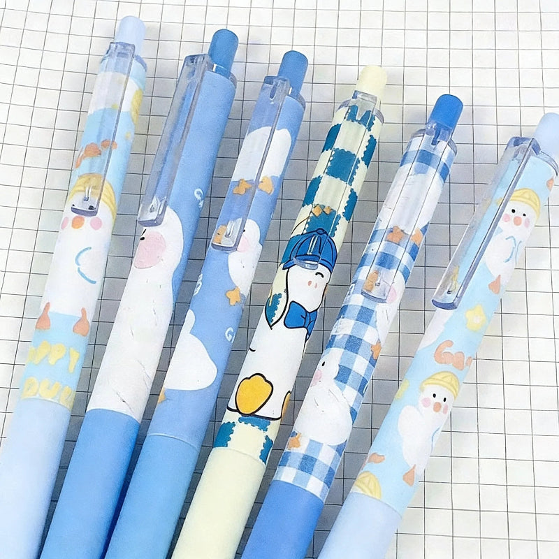 Five cute cartoon gel pens with blue and white patterns, including checkered designs, arranged diagonally on a white grid paper background.