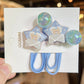 Star-shaped hair clips with teddy bear design on a white card, held by a hand.