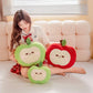 Woman sitting on a couch holding three plush apple toys.