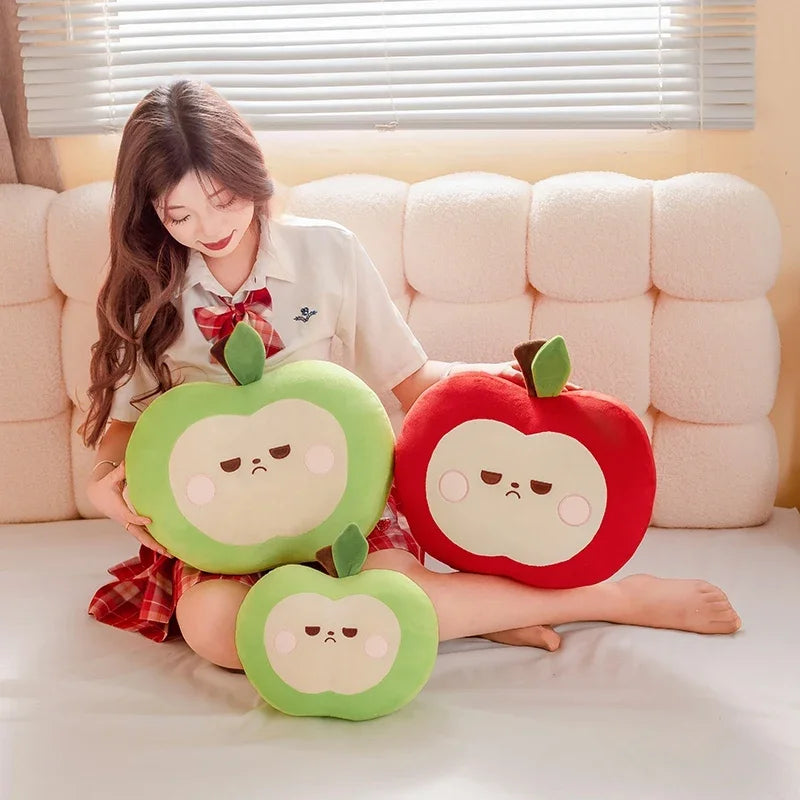 Woman sitting on a couch holding three plush apple toys.