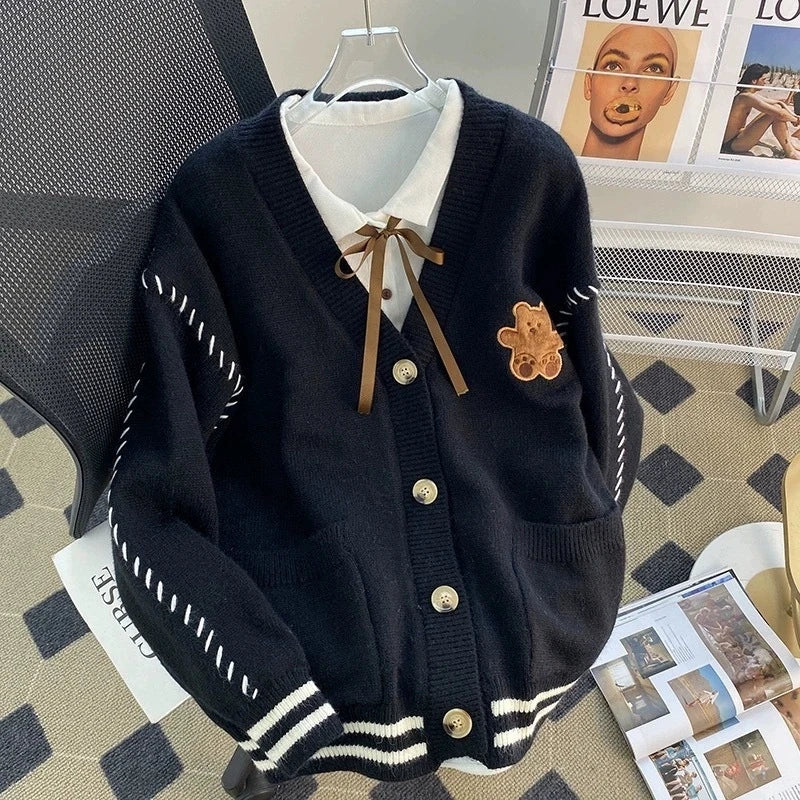 Sweet Teddy Bear Cardigan black edition with a bear sown into the chest area whilst the sleeves have large white stitches where they have been joined and black strips on the wrist cuffs with white, black and white trim.