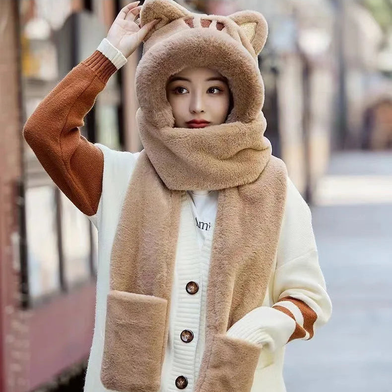 Person wearing a kawaii beige winter cat hat, scarf, and gloves with a blurred background