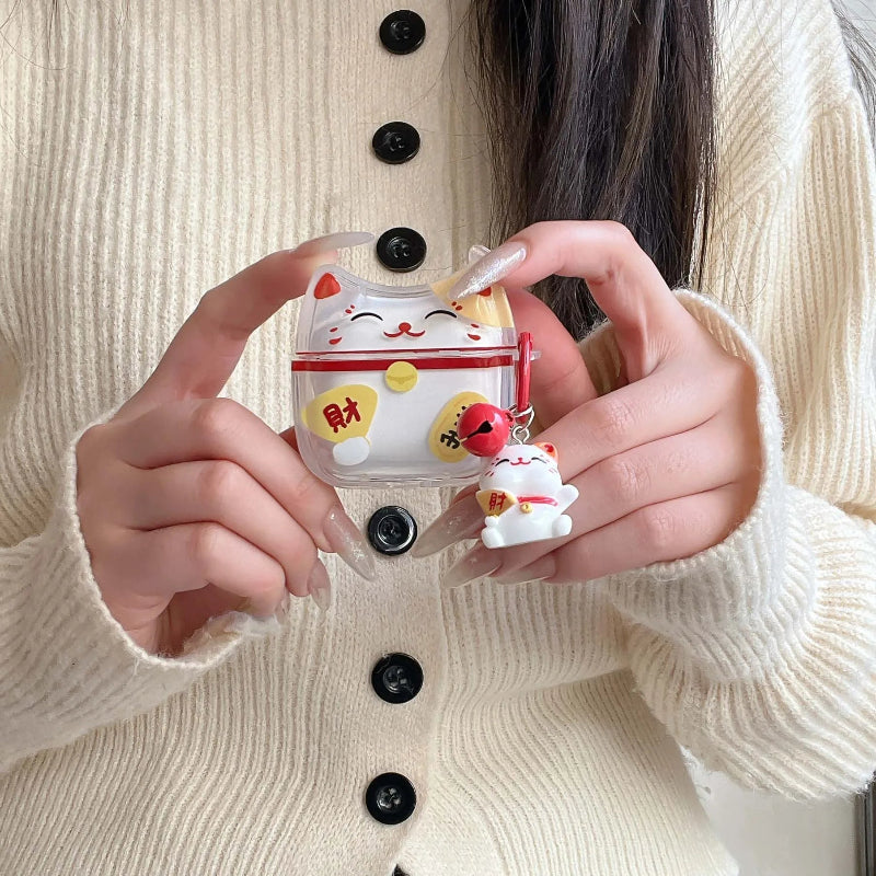 Person holding a cute maneki neko shaped air pod case with a beige sweater.