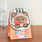 Small calendar with a cute animal design and '2026' text on a wooden surface.
