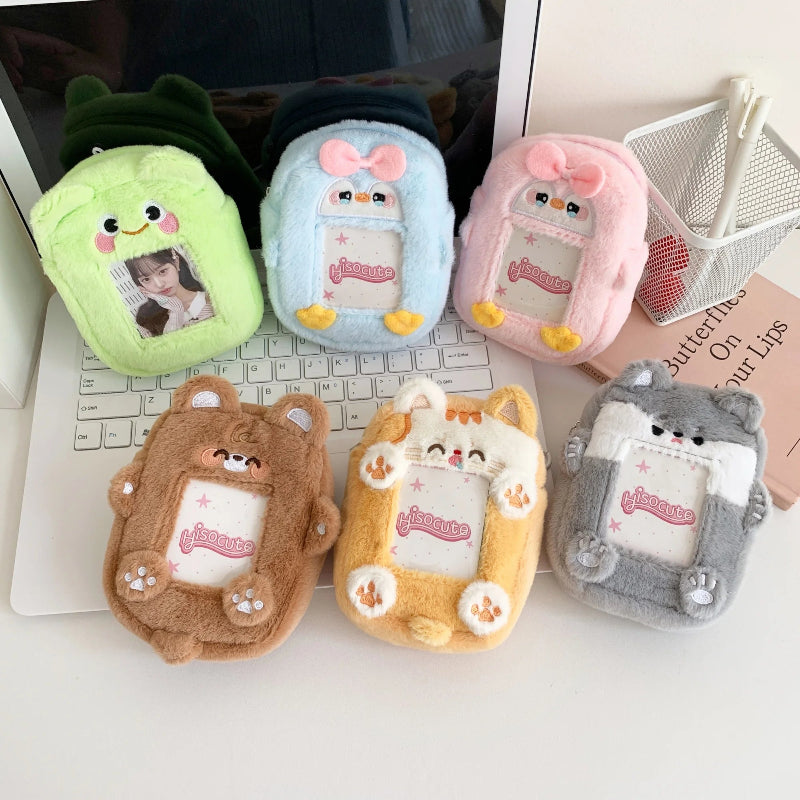 Set of plush photocard pouches with animal designs on a laptop keyboard.