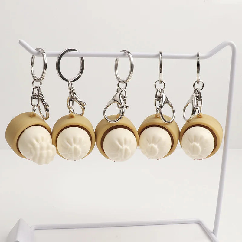 Set of five key rings with beige and white circular designs on a white stand.