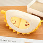 Plush toy resembling a durian with a face on a wooden surface